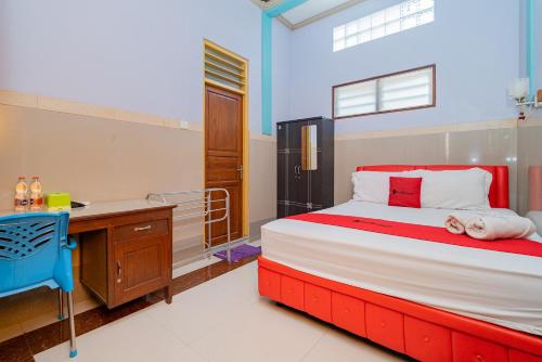 een slaapkamer met een bed en een bureau bij RedDoorz Syariah near Alun-Alun Bojonegoro in Bojonegoro