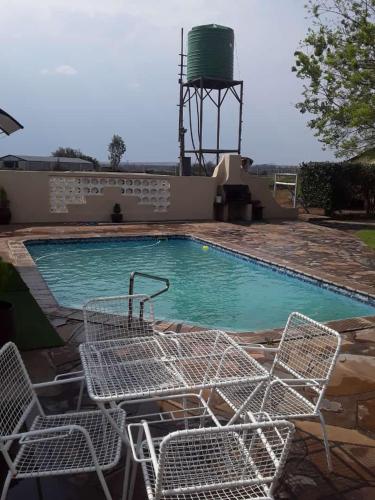 a swimming pool with chairs and a water tower at Brandwag Pool Room in Prieska