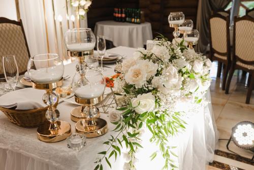 a table with white flowers and glasses on it at Na Pagorbi Lutsk in Luts'k