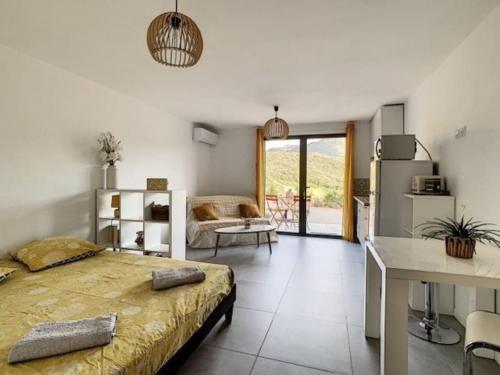 une chambre avec un lit et un bureau et une cuisine dans l'établissement Joli Studio au cœur du maquis, à Ocana