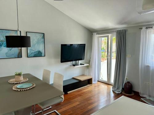 a living room with a table and a television on the wall at Deluxe Suites Mandić in Omiš