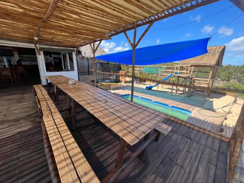 a wooden table with a blue umbrella on a deck at Mango Beach Resort in Praia do Tofo