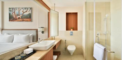 a white bathroom with a sink and a shower at Golden Tulip Jalandhar in Jalandhar