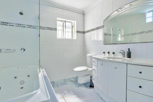 La salle de bains blanche est pourvue d'une baignoire et d'un lavabo. dans l'établissement Gorgeous 2 Bedroom House Ultimo 2 E-Bikes Included, à Sydney