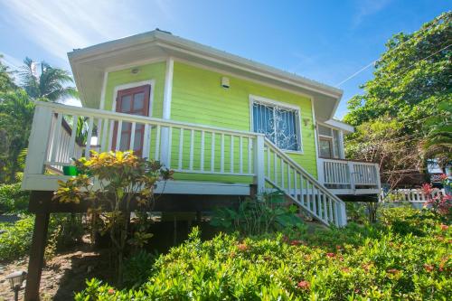 a small yellow house with a porch and a balcony at Sand Dollar Bungalow in Roatan