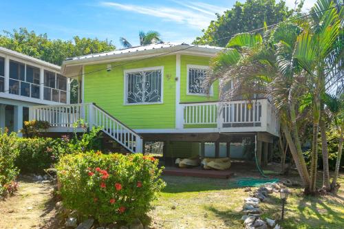 a green house with a porch and a balcony at Sand Dollar Bungalow in Roatan