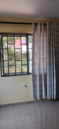 una sala de estar con una ventana con cortinas en M&R Property., en Ukunda