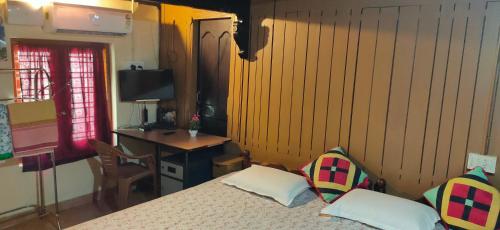 1 dormitorio con 1 cama con 2 almohadas y escritorio en Kuttickattil Pool Home Stay Kumarakom, en Kumarakom