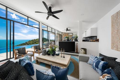 a living room with a ceiling fan and a table at Luxury Blue Coco Sea View Villa - 4x4 SUV included in Koh Samui 
