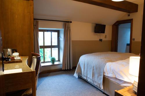 a bedroom with a bed and a desk and a window at Ye Olde Cheshire Cheese in Longnor