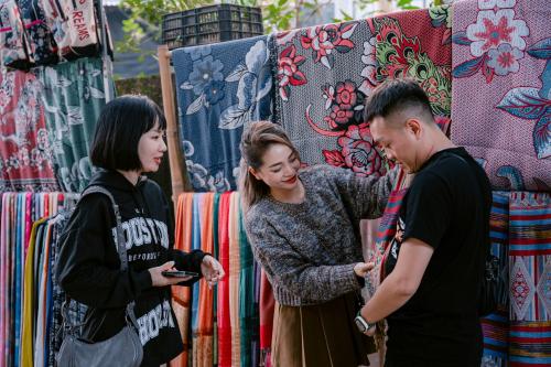 a group of people standing in front of a display of quilts at Mai Chau Mountain View Resort in Mai Chau