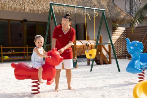 a woman playing with a child on a playground at Emerald Faarufushi Resort & Spa - Deluxe All Inclusive in Raa Atoll