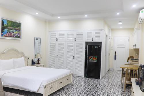 a bedroom with a large bed and a black refrigerator at Luxe Paradise Suites Hotel Dich Vong Hau in Hanoi