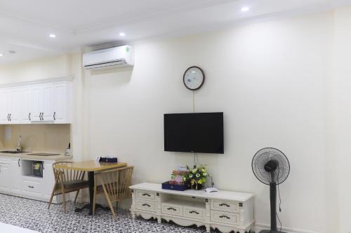 a kitchen with a table and a clock on a wall at Luxe Paradise Suites Hotel Dich Vong Hau in Hanoi