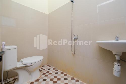 ein Badezimmer mit einem weißen WC und einem Waschbecken in der Unterkunft Grand Kencana Guesthouse near Wisata Bahari Lamongan Mitra RedDoorz in Paciran