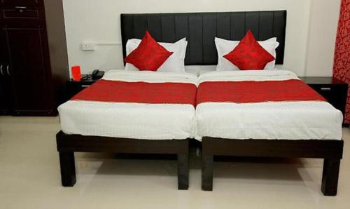 FabExpress Majestic Le Frank في Kazhakuttam: سرير ومخدات حمراء عليه في غرفة
