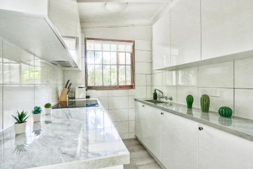 a white kitchen with a large marble counter top at Comfortable 2 Bedroom House Paddington 2 E-Bikes Included in Sydney