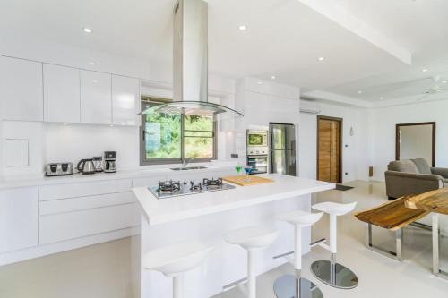 a white kitchen with a counter and stools at Villa 7 chambres vue mer in Ban Khlong Mae Nam