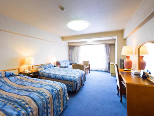 una camera d'albergo con 2 letti e una scrivania di Yuzawa New Otani a Yuzawa