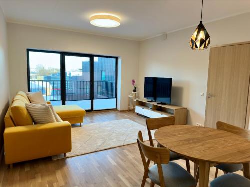 ein Wohnzimmer mit einem gelben Sofa und einem Tisch in der Unterkunft Riia 22 Apartment in Tartu