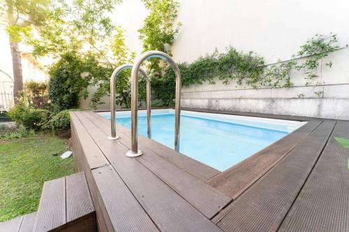 une terrasse en bois avec une piscine avec deux poignées dans l'établissement Superbe appartement avec jardin piscine, garage, à Nice
