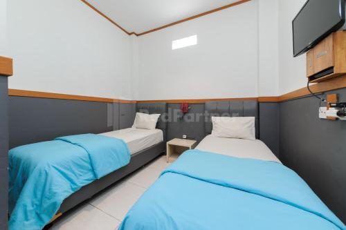 2 letti in una camera con TV di Ian Hotel Jaksa Mitra RedDoorz a Giacarta