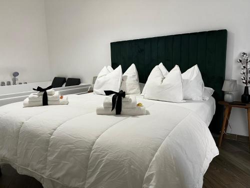 a large white bed with white pillows and a green headboard at Sea fly guest house in Fiumicino