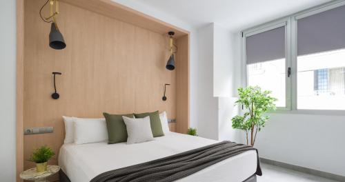 1 dormitorio con 1 cama con almohadas blancas y verdes en Tusity One, en Las Palmas de Gran Canaria