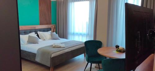 a bedroom with a bed with a table and a green wall at Apartmenthaus Oborishte in Panagyurishte