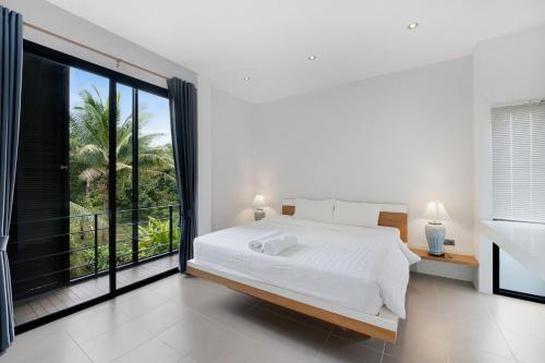 a bedroom with a white bed and a large window at Ana's House in Amphoe Koksamui