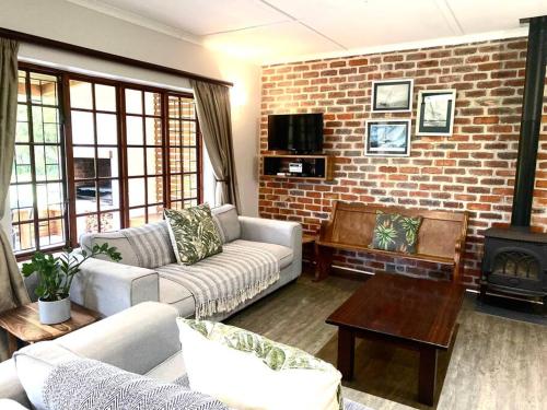 a living room with two couches and a brick wall at The Croft cottage in Knysna