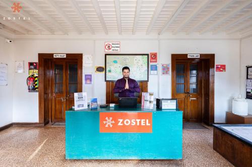 a man sitting at a desk in a room at Zostel Ooty in Ooty