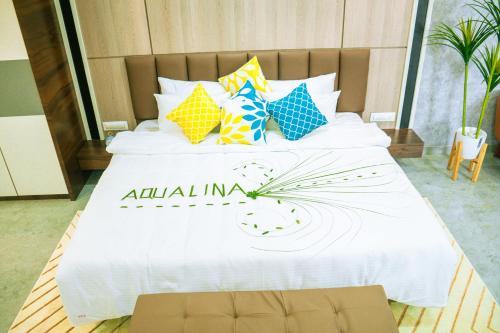 a large white bed with colorful pillows on it at Aqualina in Bhogwe