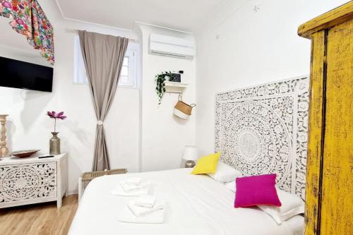 a white bedroom with a white bed with pink and yellow pillows at Small & cozy near Piazza Navona in Rome