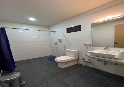 uma casa de banho com um WC, um lavatório e um espelho. em Ixoras Hotel Victoire em Kinshasa