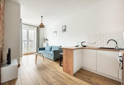 Il comprend une cuisine et un salon doté d'un canapé bleu. dans l'établissement Wola Homely Apartment #88, à Varsovie