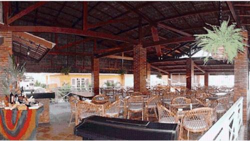 a restaurant with tables and chairs in a building at Bouganville Hotel in Beberibe