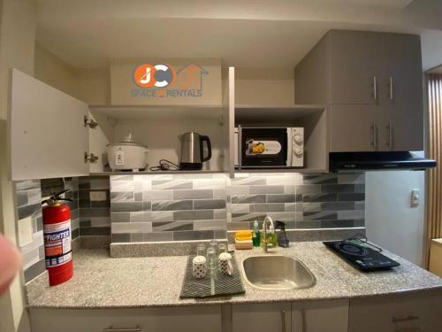 a kitchen counter with a sink and a microwave at JC SpaceRentals 127B Amani Grand Resort Residences, balcony pool view, Ground floor, 5 mins frm airport, free wifi, Netflix in Pusok