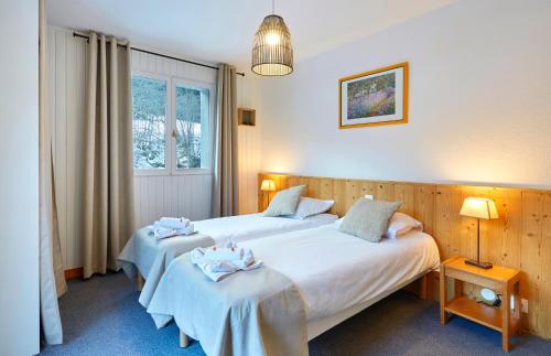 a bedroom with two beds and a window at Hôtel Eliova l'Eau Vive in Châtel