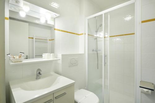ein weißes Bad mit einem Waschbecken und einer Dusche in der Unterkunft Hôtel Eliova l'Eau Vive in Châtel