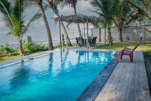 - une piscine avec une chaise rouge à côté d'une maison dans l'établissement En Ocean Infinity Pool Villa Overlooking Sea ,Beach Touch, à Alibaug