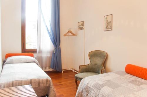 Cette chambre dispose de deux lits, d'une chaise et d'une fenêtre. dans l'établissement Ponte San Lorenzo apartment, à Venise