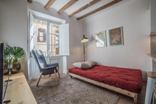 sypialnia z czerwonym łóżkiem i krzesłem w obiekcie Born Sunny Apartment (self check-in) w Barcelonie