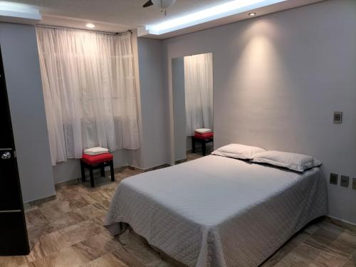 1 Schlafzimmer mit einem weißen Bett und 2 Stühlen in der Unterkunft AMG in Tehuacán