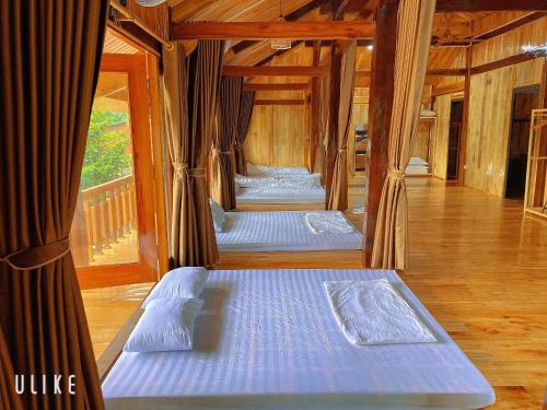 three beds in a room with wooden floors at Nam Nam Homestay in Bản Cong Na