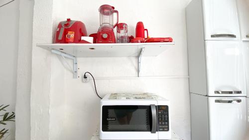 a white microwave with a shelf on the wall at Hostel Canto Zen in Salvador