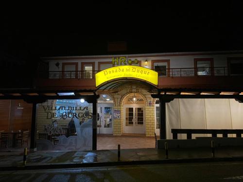 un edificio con una señal amarilla delante de él en HOSTAL-RESTAURANTE POSADA DEL DUQUE en Villalbilla de Burgos