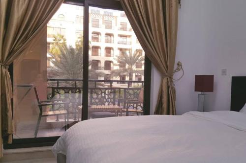 a bedroom with a bed and a view of a balcony at Studio Luxury Apartment by Mamzar Beach in Dubai