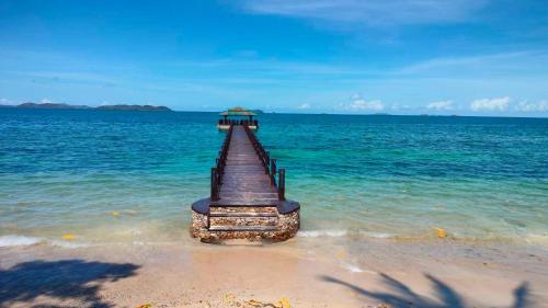 a pier sticking out of the water on a beach at Alam Indah Busuanga Beach and Villas in Busuanga