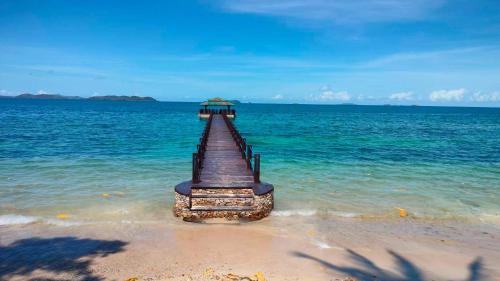 un muelle saliendo del agua en una playa en Alam Indah Busuanga Beach and Villas, en Busuanga